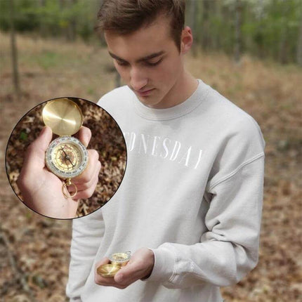Brass Pocket Compass With Luminous Display For Outdoor Navigation held by hiker in forest, compact brass body with copper shell visible