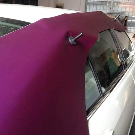 Black Vehicle Magnet Holder for Graphic Sign Application being used to steady purple vinyl graphic on car roof during installation