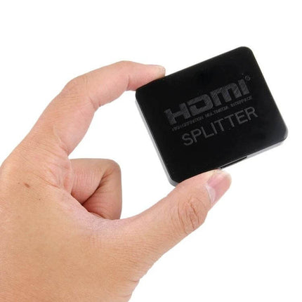Hand holding compact black HDMI 1x2 Splitter for Connecting One Source to Two Displays mirroring laptop to TV and projector