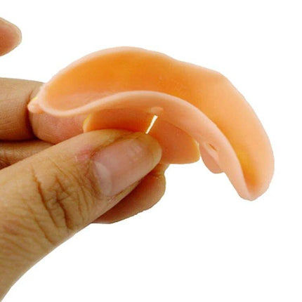 Halloween Bucktooth Dentures 5-Piece Prank Set for Parties - close-up of flexible PVC bucktooth denture held between fingers for costume use