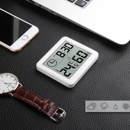 Home Humidity And Temperature Monitor Clock With 3.2-Inch LCD on desk showing digital time, temperature and humidity readings near phone and watch