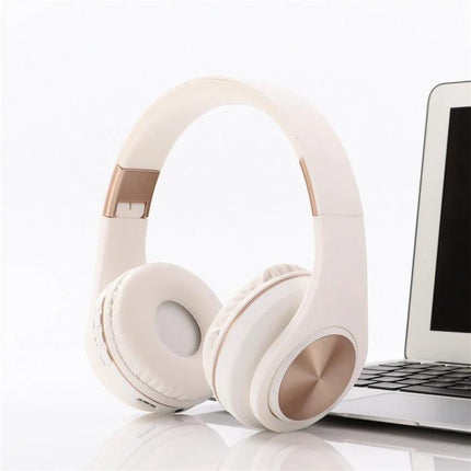 Candy Color Bluetooth Headphones With On Ear Controls For Daily Use shown in pastel white with rose gold accents next to laptop