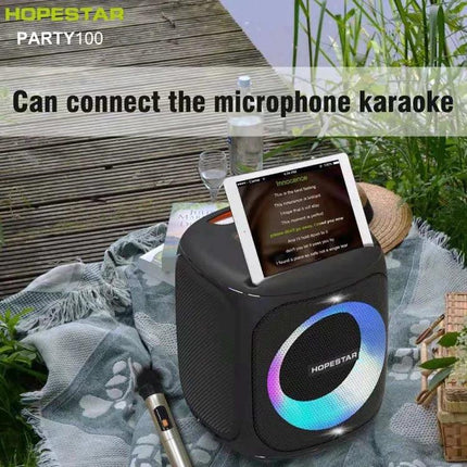 HOPESTAR Compact Portable Bluetooth Speaker For Outdoor Travel shown at picnic with tablet, mic, splash‑resistant design for camping