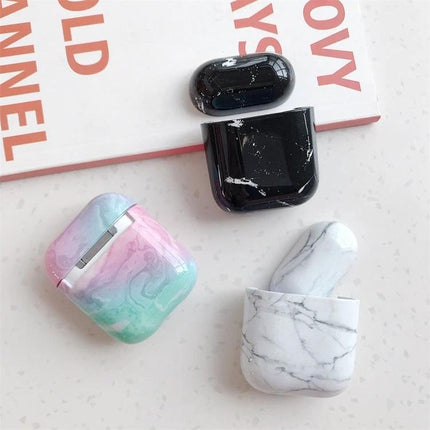 Marble Design Protective Case for Daily AirPods Carry showing pastel, black, and white marble AirPods cases on a table