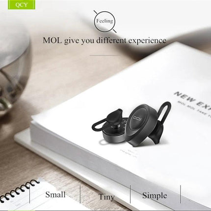 QCY Single Wire Bluetooth Earphone For Commuting And Calls black single-wire earbud with mic on a book for hands-free use