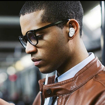 QCY Single Wire Bluetooth Earphone For Commuting And Calls worn by commuter using phone, single-wire Bluetooth earbud with mic