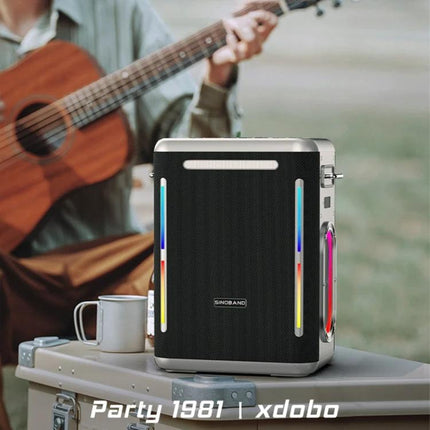 SINOBAND Portable Outdoor Speaker With Mood Light For Picnics sitting on picnic table with guitar and mug, Bluetooth party speaker