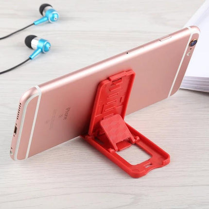 Portable Adjustable Stand for Smartphones and Tablets holding a rose gold phone at an angled viewing position, red foldable travel stand for desk or commute