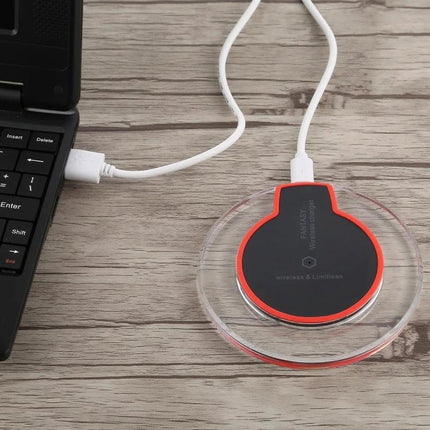 Fantasy Wireless Charger for Daily Home Phone Use on nightstand-style wooden desk next to laptop, clear round pad with red-trimmed black top plugged in
