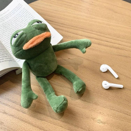 Protect your earbuds daily with a plush frog case on the go: green plush frog case beside AirPods showing built-in charging access