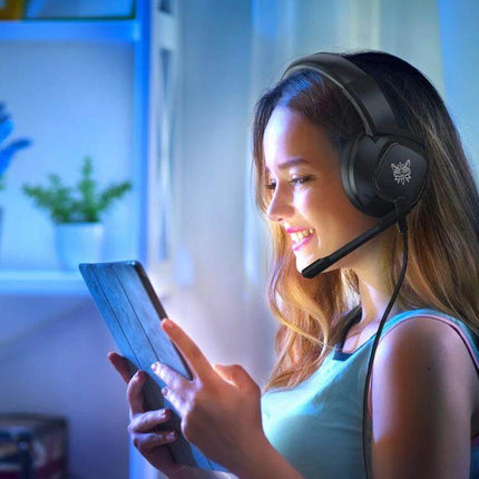 Onikuma Gaming Headset With Adjustable Lightweight Comfort Fit worn by smiling gamer using tablet in cozy streaming setup