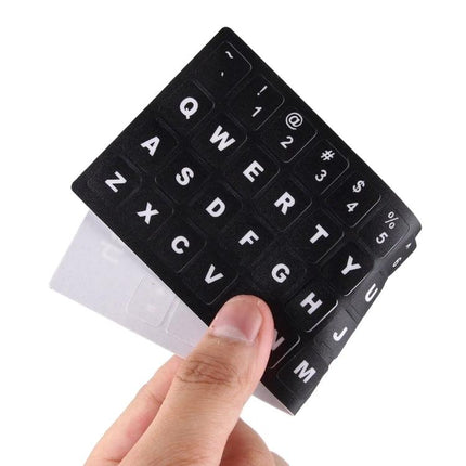 English Keyboard Stickers with White Letters for Laptops and Notebooks applied to black laptop keys, easy-read white letters, flexible sticker sheet