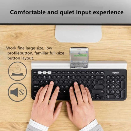 Logitech K780 Multi-Device Wireless Keyboard for Easy Typing on desk with hands typing and smartphone docked