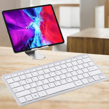 Wireless Bluetooth Keyboard with Portuguese Layout shown slim white keyboard beside a tablet on a desk