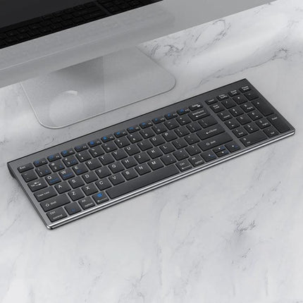 Three-Mode Wireless Bluetooth Keyboard for Everyday Typing on a slim wireless keyboard next to a desktop monitor, quiet low-profile keys