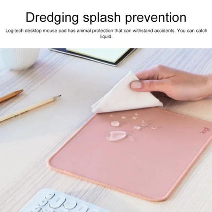 Logitech Soft Surface Mouse Mat for Comfortable Daily Use showing pink waterproof surface being wiped clean with water droplets
