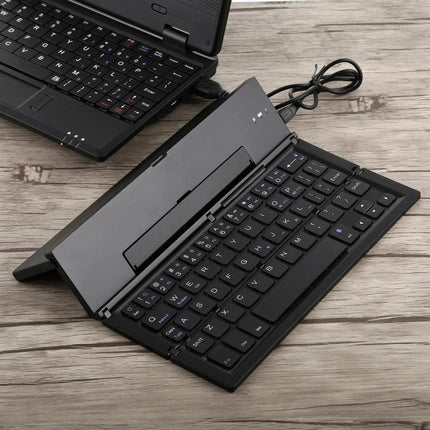 GK608 Ultra-Thin Foldable Bluetooth Keyboard with Built-in Holder shown open on a wooden surface next to a laptop, portable travel keyboard
