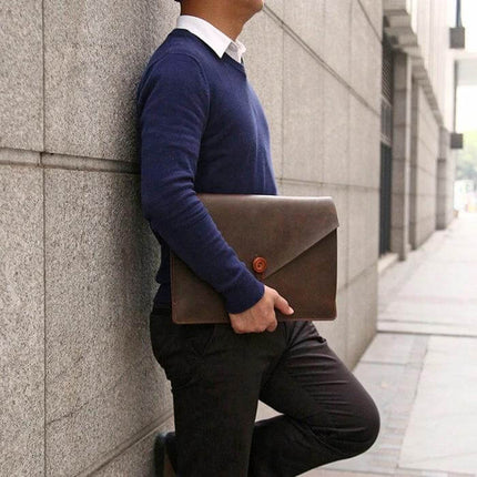 Genuine Leather Protective Sleeve for 13.3 Inch Laptops in brown held by professional commuting man against urban wall