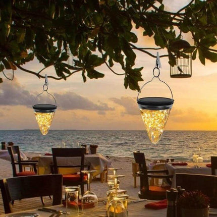 Solar Conical Starlight Pendant Lamp IP55 Outdoor Garden hanging over beachfront dining, solar-powered conical starlight pendant glowing at sunset