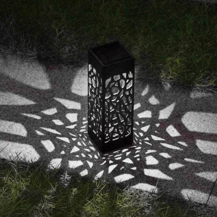 Outdoor Hollowing Out Solar Energy Garden Lawn Lamp For Pathways casting decorative patterned light on a garden path at night