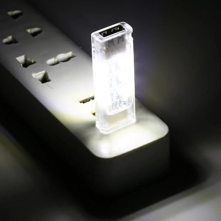 Compact Stackable USB Light for Daily Desk and Travel Use plugged into power strip, compact translucent USB LED illuminating dark workspace