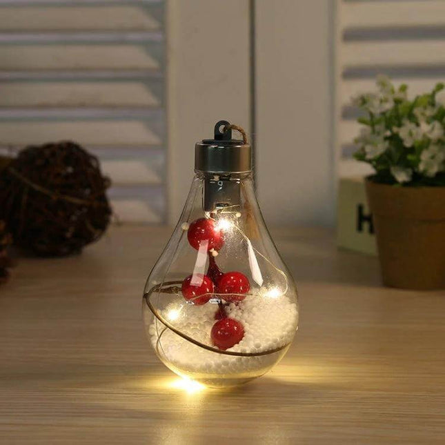 LED Transparent Christmas Ball Ornaments 2 Pack For Tree glowing transparent plastic bulbs with warm LED lights and red decorative berries on tabletop