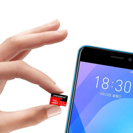 Stickdrive 128GB Micro SD Memory Card for Everyday Storage held between fingers next to a smartphone illustrating portable 128GB storage