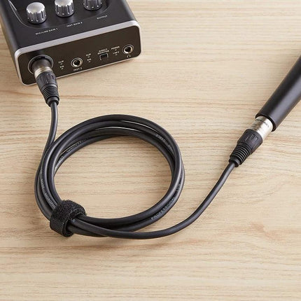 XLR Microphone Cable for Everyday Home Audio Connections coiled between microphone and audio interface on wooden desk