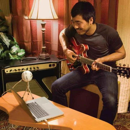 Logitech Microphone for Everyday Home Recordings and Calls set up on a desk mic capturing clear guitar and vocal audio in a cozy home office