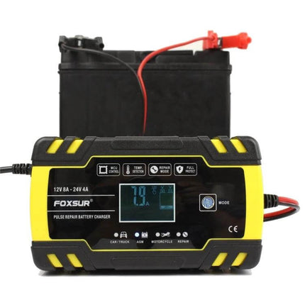 Foxsur 12V-24V Battery Charger for Cars and Motorcycles connected to a car battery showing LCD and clamps