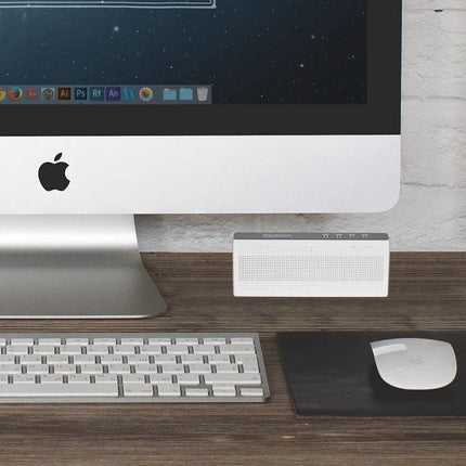 Compact Portable Bluetooth Speaker For Everyday Music placed on desk beside iMac keyboard and mouse for streaming and hands-free calls