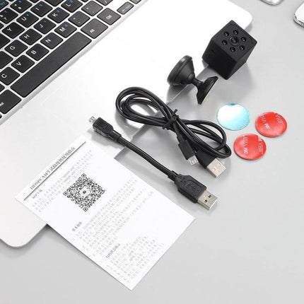 Smart Home WiFi Security Camera with Motion Detection and Night Vision showing camera, USB cable, mount, adhesive pads and manual on a desk