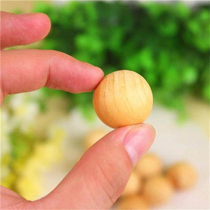Natural Camphor Wood Balls 5pc Set for Moth and Insect Repellent - single 2.5cm camphor wood ball shown between fingers, non-toxic storage sachet