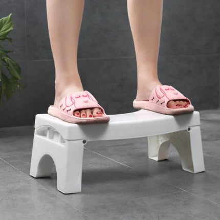 Non-Slip Toilet Foot Stool Foldable For Kids, Easy Squat Support — white foldable non-slip stool shown with child’s feet in pink slippers creating comfortable squat position