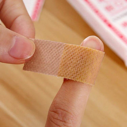 Noning Waterproof Band Aid 100 Count Box For Everyday Wounds - close-up of beige adhesive bandage on fingertip, 8.5 x 2.9 cm waterproof wound coverage