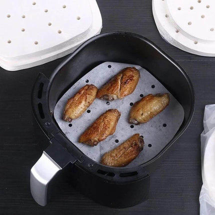 Oil-Absorbing Round Parchment Paper With Hole For Air Fryer And Oven placed in air fryer under chicken wings to absorb oil and prevent sticking