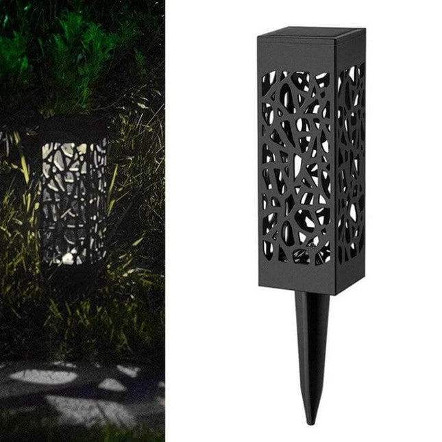 Outdoor Hollowing Out Solar Energy Garden Lawn Lamp For Pathways placed along a garden edge casting decorative patterned light at night