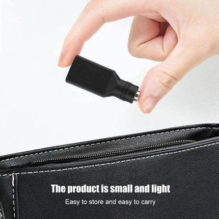 USB Female to 5.5mm Adapter for Device Connections - compact black adapter held above a bag, portable solution for mismatched USB and 5.5x2.1mm plugs