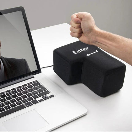 Big Enter Button USB Pillow for Relaxing at Your Desk - Black next to laptop being pressed as a USB-powered oversized Enter key pillow