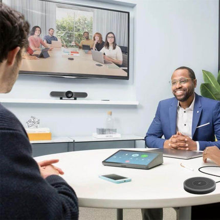 Logitech Omnidirectional Extension Microphone for Large Conferences placed on a round table in a modern meeting room with video conferencing setup