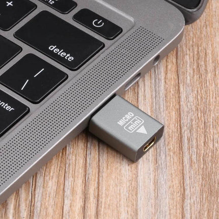 Mini HDMI to Micro HDMI Adapter for Device Connections plugged into laptop USB-C area, compact gray Mini HDMI male to Micro HDMI female converter