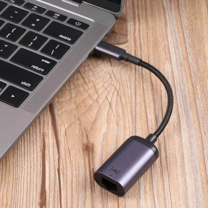USB-C to RJ45 Ethernet Adapter Cable for Network Use plugged into laptop USB-C port on wooden desk, showing RJ45 port and braided cable