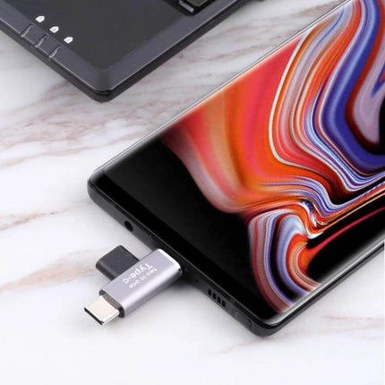 USB-C Female to Male Adapter for Connecting Devices plugged into smartphone for charging and data transfer with laptop nearby
