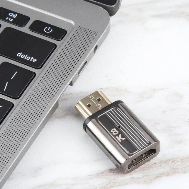 HDMI Female to DisplayPort Male Adapter for Video Devices next to laptop showing compact 8K-capable adapter for connecting HDMI devices to DisplayPort monitors