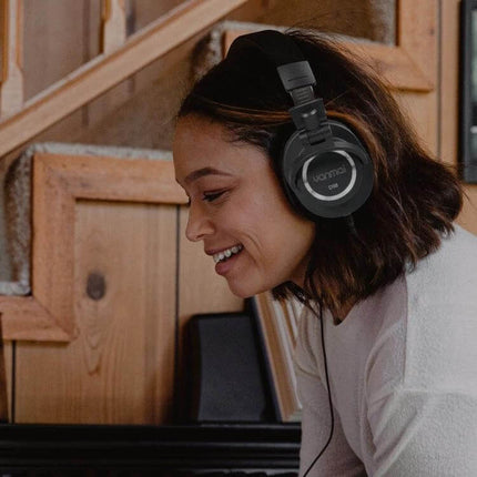 Yanmai Studio Monitoring Headphones With Comfortable Fit worn by smiling woman in wood-paneled studio for accurate closed-back monitoring