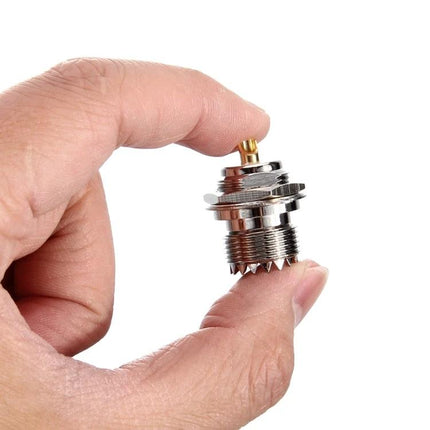UHF Female to KY Connector for Antenna and Cable Links held between fingers, metal adapter for antenna and cable assemblies