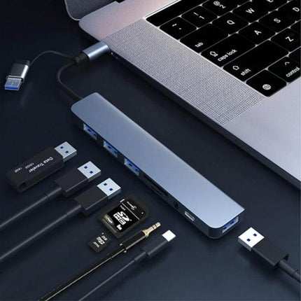 8-in-1 USB and USB-C Multifunctional Docking Station connected to laptop with multiple USB drives, SD cards, audio jack and HDMI port