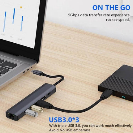 BYL USB-C Multi-Port Docking Station with Ethernet Adapter connected to laptop with external SSD and USB devices on wooden desk