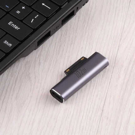 USB-C Female Charging Adapter for Microsoft Surface Devices shown next to laptop keyboard, compact metallic plug-and-play charger