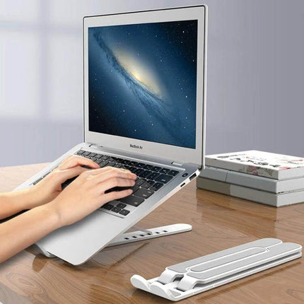 Foldable Adjustable Laptop Stand for Home and Office Use showing silver laptop elevated on adjustable white stand